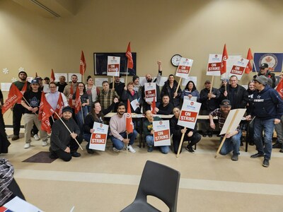 A group of people holding strike signs and red Unifor flags. (CNW Group/Unifor)