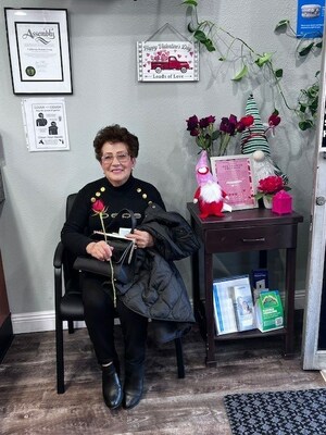 A delighted patient at the Bellflower office expresses a genuine smile with the rose she received during her dental visit.