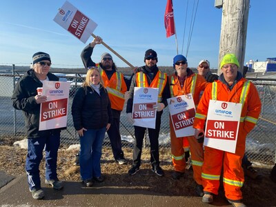 A group of striking workers stand with picket signs. (CNW Group/Unifor)
