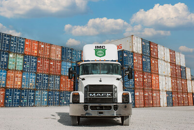 IMC Truck parked in front of a stack of containers at a depot.