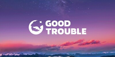 A circular logo of a phoenix next to the words "GOOD TROUBLE", with mountains and sky in the background.