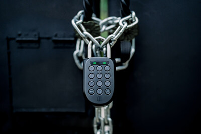 a rugged and durable pin code enabled smart padlock from igloohome that is locking an exterior gate with a stainless steel chain. The color of the padlock and gate are both black.