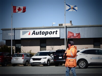 A Unifor member waves a flag as they walk in front of the Autoport office in Eastern Passage, Nova Scotia. (CNW Group/Unifor)