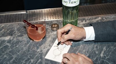 Stanley Tucci sketching botanicals besides 'The TENacious' cocktail and new Tanqueray No. TEN bottle (Photo Credit: Matt Holyoak)