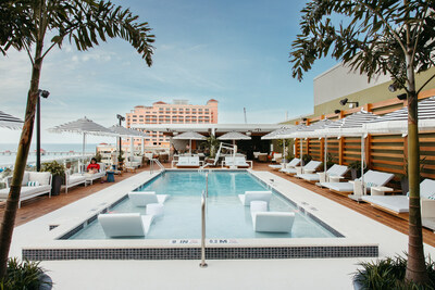 Elegant rooftop pool and bar at Hiatus Clearwater Beach, with chic poolside loungers, inviting crystal-clear water, and stylish bar. The panoramic backdrop reveals sweeping views of the coast, symbolizing the perfect fusion of luxury and stunning seaside scenery.