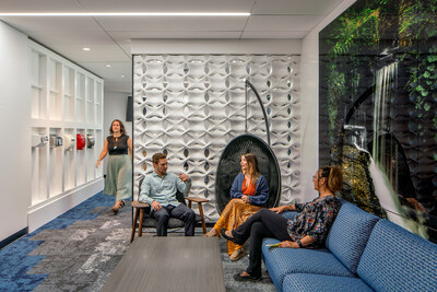 Colleagues engage in a casual conversation in a cozy office nook, blending natural design elements with comfort.