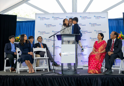 Tampa business leader and philanthropist Sidd Pagidipati holds his children, Aria and Aren, while announcing a transformative $50 million donation to honor his parents' legacy as health care providers, their 50th wedding anniversary and their 50th anniversary of coming to the United States. Pictured left to right: Ishan, Ami Pagidipati, Arjun, Rahul Pagidipati, Aria, Sidd Pagidipati, Aren, Dr. Rudrama Pagidipati, Dr. Devaiah Pagidipati and Srujani Pagidipati.