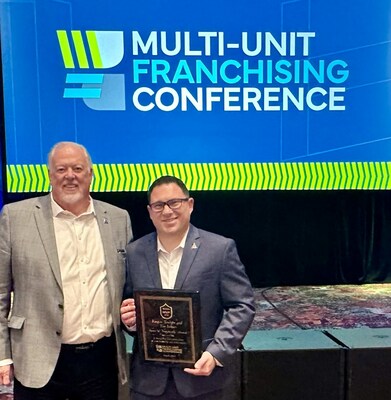 Steve White, President and COO of PuroClean, and Keegan Trudgen pose with Spirit of Franchising Award at 2024 MUFC Conference.