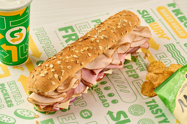 Subway footlong sandwich on honey oat bread with drink cup and chips