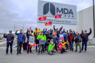 Workers with raised fists stand in front of the MDA Space headquarters in Brampton, Ontario (CNW Group/Unifor)