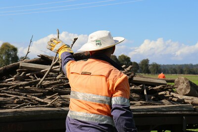 A Rural Aid volunteer helps clear flood debris on a Taree farm.