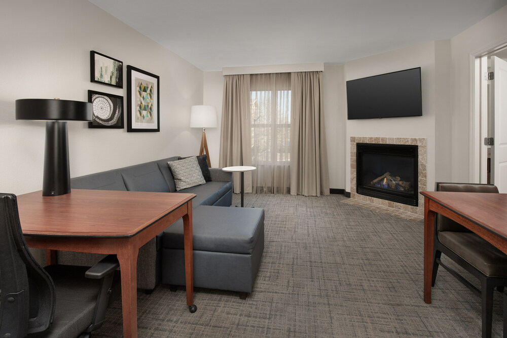 Cozy living area in a one-bedroom suite at Residence Inn Fayetteville, NC, featuring a pull-out couch, a warm inviting fireplace, and contemporary decor.