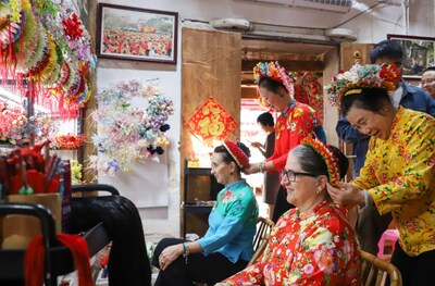 La photo montre des touristes étrangers en train de découvrir les coiffes fleuries de Xunpu, un patrimoine immatériel national, dans le village de Xunpu. (PRNewsfoto/Xinhua Silk Road)