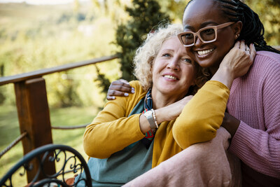 Une femme blanche ge sourit en s'appuyant sur l'paule d'une femme noire portant des lunettes. (Groupe CNW/Azrieli Foundation (The Canadian Centre for Caregiving Excellence))