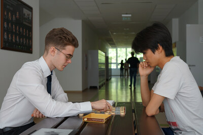 Eleventh-grade students Sanyi (left) and Li Fulin of the Hungarian-Chinese bilingual school in Budapest, Hungary play Chinese chess after a class. (Photo by Yi Lin)