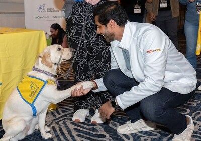 Synchrony volunteer greets a Canine Companions future service dog puppy. (Photo credit: TheWrightVision for Synchrony)
