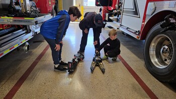 Behind the scenes while filming a #LifeSkillsNow workshop on what to do in an emergency - Firefighter Izzy Magufee from Byron Township FD shows John and Gabe Kimball the "jaws of life."