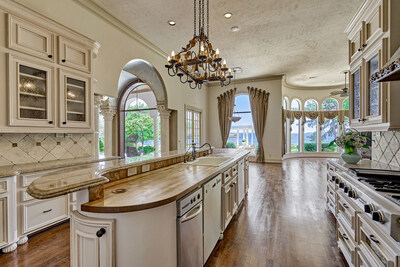 A chef’s kitchen with oversized center island offers easy access to a waterfront dining nook and to the outdoor living areas, which include a summer kitchen, custom pool and spa, paved pool deck and sprawling greenspace. The property offers nearly 150 ft of frontage on the lake, and can readily accommodate a boat dock or boathouse. LakefrontLuxuryAuction.com.