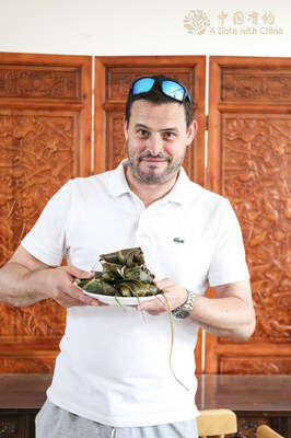 Nick Ive, a British editor with China Daily, poses for a photo with a plate of zongzi in Weihai, East China’s Shandong province, on June 7, 2024. [Photo provided to chinadaily.com.cn]