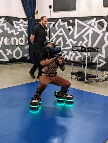 Another person using EKTO VR's robotic footwear and VR headset, squatting in a different VR session, highlighting the immersive experience.