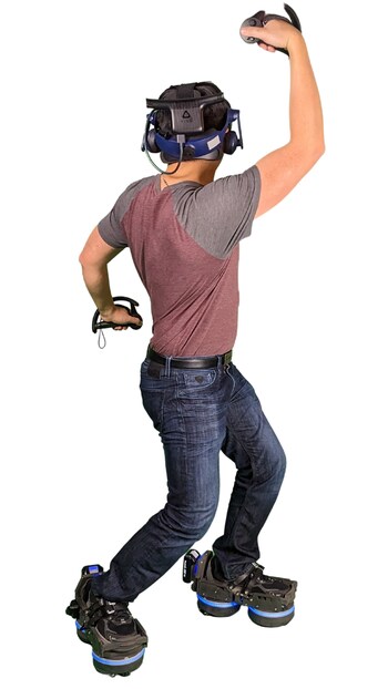 A man in a VR headset and hand controllers poses as if engaged in a VR activity, showing the functionality of EKTO VR's innovative footwear.