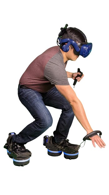 A man wearing a VR headset and hand controllers crouches down, demonstrating the flexibility and immersive capabilities of EKTO VR's robotic footwear.