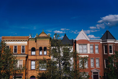 Alt Text: Five brick townhomes with a blue sky above and a few trees in the foreground.
Credit: Lexey Swall for The Pew Charitable Trusts