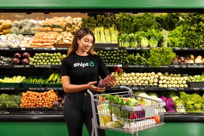 Shopper with Shipt standing in front of grocery store produce aisle