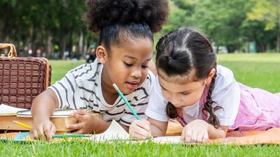 Children spend time writing outdoors during the summer.