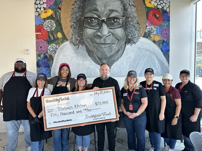 Smithfield’s Kansas City employees present a $50,000 check after volunteering at Thelma's Kitchen to help celebrate the cafe's grand reopening.
