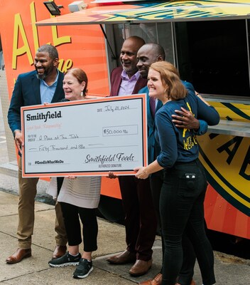 Steve Evans, vice president of community development, Smithfield Foods, presents a $50,000 donation check to A Place at the Table during the ribbon cutting ceremony.