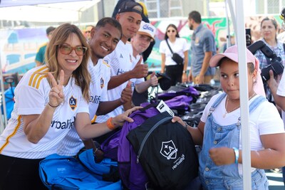 Ibi Montesino, managing director for Herbalife North America, and LA Galaxy players Mauricio Cuevas, Edwin Cerrillo, and Tucker Lepley distribute backpacks filled with school supplies to South Central Los Angeles youth and their families at A Place Called Home's annual Back-to-School Event. Herbalife and the LA Galaxy donated the 1,000 backpacks through their Joint Community Partnership Fund.