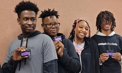Students at the Rooted School in Indianapolis show off the debit cards (with card numbers covered) that hold the $50 a week guaranteed income the school and researchers are giving them to teach financial literacy. (Patrick O’Donnell)
