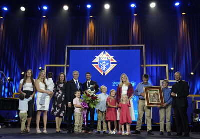 Joe and Tiffany Ampe, with 11 of their 13 children, accept the International Family of the Year award from Supreme Knight Patrick E. Kelly at an awards session prior to the 142nd Supreme Convention in Québec City on Aug. 5, 2024. Joe Ampe, a Knight from Marquette, Mich., and his family were recognized for their service to their parish and their community, particularly their efforts to deliver humanitarian aid to Ukraine, the home country of three of their adopted children. (Photo by Paul Haring)