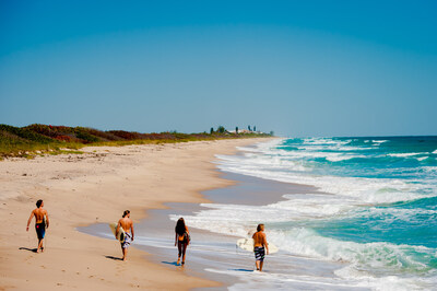 Surfers walking along the shore in Cocoa Beach on Florida's Space Coast.