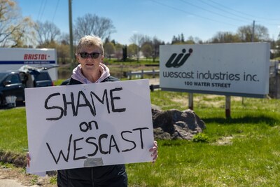 Wescast worker Laura Collison holds a sign reading "Shame on Wescast" in front of a Wescast Industries Inc. sign in Wingham, Ontairo. (CNW Group/Unifor)