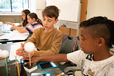Two middle school boys discuss the angle of the sun's light as it relates to phases of the moon.