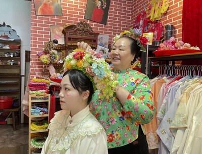 A foto mostra um morador prendendo um chapéu florido para uma turista no vilarejo de Xunpu, na cidade de Quanzhou, província de Fujian, no sudeste da China. (PRNewsfoto/Xinhua Silk Road)