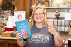 Old Country Store team member Grace Coleman poses with Former Blue Bell CEO Ricky Dickson's book and a scoop of Blue Bell's strawberry ice cream.