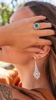 Model, wearing diamond earrings and a diamond and emerald ring. Image courtesy of Christoffel Jewelry