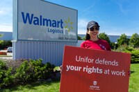 Walmart worker outside of company warehouse holding a sign that reads 'Unifor defends your rights at work'. (CNW Group/Unifor)