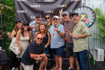 A group of attendees from the Kentucky Bourbon Festival pose next to the CaskX Bourbon Wheel after taking a spin. Winners were rewarded with a pour from a top shelf bourbon.