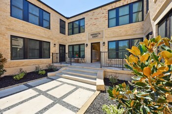 Revitalized courtyard of Marquita Court Apartments, featuring original 'Marquita Court' lettering and new pavers blending historic charm with modern elegance