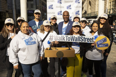 The Hispanic Association on Corporate Responsibility team holding Walk to Wall Street signs while standing at the podium at Bowling Green Park in Lower Manhattan at the conclusion of the Walk to Wall Street on October 11.