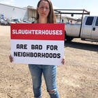 An activist holds a sign at a protest outside Denver's slaughterhouse.