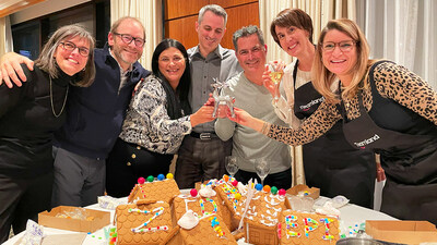 A group of employees at a corporate office holiday party smiling with gingerbread house decorating competition hosted by Teamland. (CNW Group/Teamland)