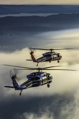 Two iconic Black Hawk helicopters flying in formation.