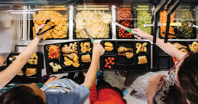 Aerial view of a line of children serving themselves colorful, healthy food for lunch in a school cafeteria