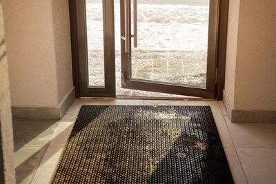 Muddy rubber doormat mounted on tiled floor inside of house entrance in winter time. Cleaning service and household concept.; Shutterstock ID 2239326863; purchase_order: winter prep; job: ; client: ; other: