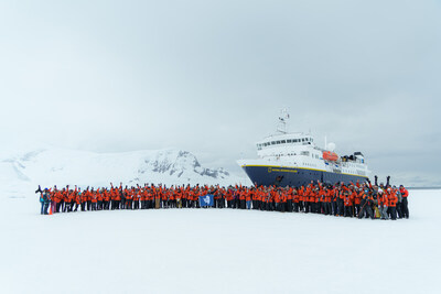 Guests on the inaugural departure of National Geographic-Lindblad Expeditions’ new 10-day Antarctica Direct: Sail and Fly the Drake Passage expedition take a group photo in front of National Geographic Explorer while parked in fast ice. (Photo Credit: Joshua Vela, Lindblad Expeditions)